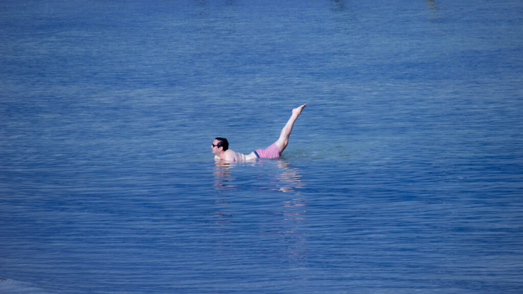 Un baigneur prend la pose dans la mer comme s'il faisait de la natation synchronisée