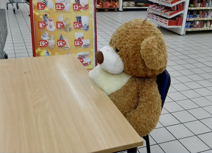 Un ours en peluche attablé dans le supermarché.